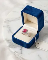 Anillo de plata 925 con piedra central ovalada de raíz de rubí en tono rojizo, rodeada por un halo de circonias brillantes.