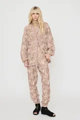Pantalón de encaje color beige con estampado floral en tono claro, de corte holgado estilo balloon con puños elásticos.