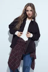 Sobrecamisa de pana color marrón oscuro, con diseño de corte amplio, cuello camisero, cierre frontal con botones y bolsillos con solapa en el pecho.