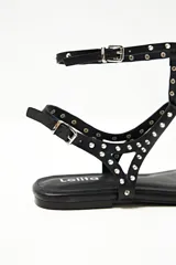 Sandalias negras tipo ojotas con tiras finas y tachas plateadas.