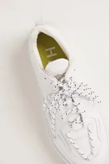Zapatillas urbanas blancas de cuero con cordones moteados en blanco y negro y suela chunky.