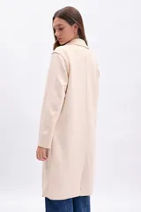 Blazer largo de mujer, color beige claro, con solapas amplias, bolsillos frontales grandes y corte recto.