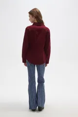 Camisa de pana color marrón, con cuello camisero, cierre frontal de botones y bolsillos en el pecho. Presenta un corte entallado y mangas largas.