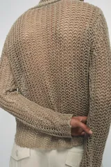Jersey de punto calado color beige, con cuello alto vuelto y manga larga, confeccionado en lino.