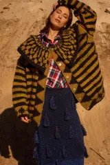 Saco de punto con diseño geométrico y rayas horizontales, cuello amplio y botones artesanales. Presenta una combinación de colores chocolate y beige.