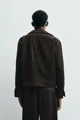 Sobrecamisa de corte cropped confeccionada en terciopelo con elasticidad. Presenta cuello solapa, cierre frontal con cremallera metálica, bolsillos de vivo en la cadera y mangas largas con puños abotonados.