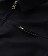 Campera tipo trucker de sarga color azul marino, con cuello de terciopelo al tono, cierre frontal de cremallera y bolsillo con cierre en el pecho.