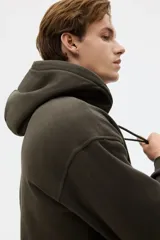 Canguro de corte holgado con capucha forrada y cordón de ajuste. Presenta hombros caídos, bolsillo frontal tipo canguro y terminaciones acanaladas en puños y ruedo. Confeccionado en mezcla de algodón con interior suave.