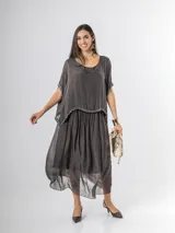 Vestido largo de seda italiana en color gris oscuro, con falda larga lisa, forro y cintura elastizada. Posee una sobrecapa con detalles de paillettes en los bordes de las mangas y la cintura.