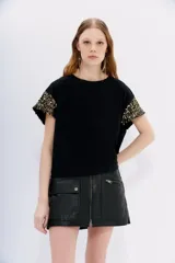 Remera de cuello redondo confeccionada en jersey de algodón, con mangas cortas caídas decoradas con lentejuelas a tono.