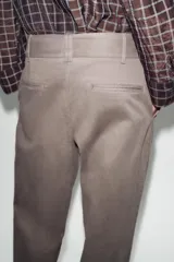 Pantalón recto color gris topo, de tiro medio, con bolsillos delanteros y falsos bolsillos de doble vivo en la espalda. Cierre frontal con cremallera, botón interior y ganchos.