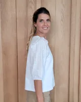 Remera blanca de algodón con cuello redondo, mangas tres cuartos abullonadas y detalle de volados en los hombros.