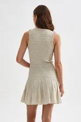Vestido corto beige sin mangas con cuerpo de nido de abeja elástico y falda corta acampanada con vuelo.