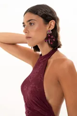 Vestido largo de encaje color bordó, con escote halter y diseño ajustado en el torso que se extiende hasta la cintura, donde continúa con una falda larga de encaje transparente.
