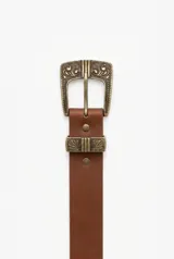 Cinturón estilo boho de cuero marrón con hebilla metálica grande y pasador decorados con grabados ornamentales estilo western.