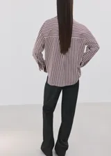 Camisa de corte recto confeccionada en mezcla de algodón y poliéster, con estampado de rayas. Cuenta con cuello camisero, manga larga con puños abotonados, bolsillo de parche en el pecho y cierre frontal con botones.