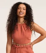 Blusa color ladrillo con escote halter, sin mangas, lazo en la espalda y flecos con caracolas en la cintura.