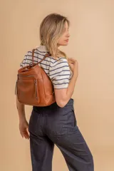 Cartera mochila versátil de cuero sintético con textura granulada, color negro. Cuenta con múltiples bolsillos frontales con cierre, correas ajustables que permiten su uso tanto como cartera de hombro o como mochila, y herrajes metálicos.