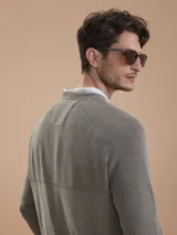 Sweater de punto verde militar con cuello redondo, mangas raglán y un pequeño bolsillo en el pecho con detalle de parche con logo.