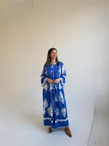 Vestido largo color azul con estampado ornamental en color blanco, escote en V con botones frontales y mangas tres cuartos con volados.