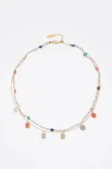 Collar doble dorado con una tira de perlas intercaladas con pequeñas piedras de colores y otra cadena metálica con dijes colgantes de piedras rectangulares y perlas. Cuenta con cierre de mosquetón y cadena de alargue.