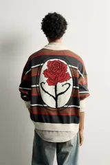 Polo de punto de algodón de ajuste relaxed, con diseño de rayas horizontales en tonos marrón, negro, rojo y blanco, cuello solapa de color crudo con abertura frontal, y manga larga con detalles en rib.