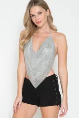 Top halter plateado confeccionado en malla metálica con pedrería, escote pronunciado y diseño con espalda descubierta.