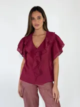 Blusa bordó de manga corta con escote en V y volados en cascada que rodean el cuello y el frente.