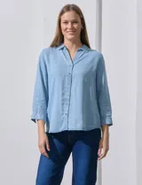 Camisa gris de tencel con cuello con solapa, escote en V y abertura central con botones. Largo de manga regulable con presilla y botón. Ruedo en espalda con tajo.