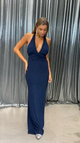 Vestido largo de fiesta color azul marino con acabado brillante, escote halter profundo y detalle de fruncido en la cintura.