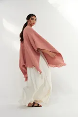 Ruana de tejido de punto con textura, color rosa claro, con flecos en el ruedo. Diseño versátil y envolvente, ideal para usar como abrigo ligero.
