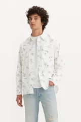 Camisa de hombre de corte relajado, color blanco con estampado floral azul, con cuello clásico, cierre con botones a presión, mangas largas con puños abotonados y dos bolsillos con solapa abotonada en el pecho.