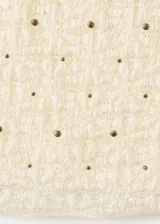 Top sin mangas de tejido texturizado con efecto arrugado y diseño entallado, de cuello redondo y color beige con pequeños detalles brillantes.