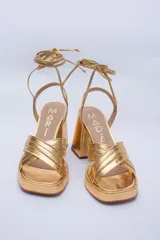 Sandalias color beige con plataforma y tacón cuadrado. Presentan tiras cruzadas en el empeine y tiras largas para atar alrededor del tobillo.