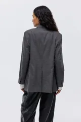 Blazer de botonadura sencilla con solapas de pico, cierre de un botón frontal, hombreras, puños con botones y bolsillos delanteros ribeteados. Presenta una abertura en la parte posterior y forro interior.