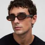 Lentes de sol modelo Lua con montura ovalada y estilizada de diseño retro. Presentan un marco con patrón de carey en tonos marrones y lentes polarizadas de color marrón con protección UV400.