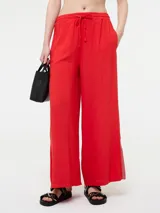 Pantalón amplio confeccionado en mezcla de lino y viscosa de color rojo. Posee cintura elastizada con cordón ajustable, bolsillos laterales y tajos en el ruedo con detalle de galón metalizado.