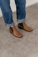 Bota corta de cuero color marrón con elásticos laterales, taco bajo y punta redondeada.