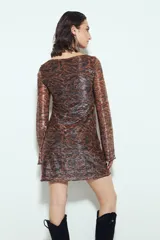 Vestido corto de manga larga, escote redondo y calce ajustado. Confeccionado en tejido liviano con estampado tipo damasco o paisley en tonos negro, marrón y dorado/plateado brillante.