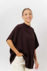 Sweater de tejido de punto color negro, con cuello semi alto y mangas cortas amplias. Presenta una silueta relajada y caída fluida.