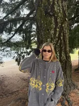 Saco de punto gris con diseño geométrico en color amarillo, cierre frontal con botones, cuello redondo y bordado de corazón pequeño en el pecho.