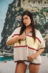 Remera de tejido de punto con diseño retro de bloques de color en crema, amarillo y rojo. Presenta cierre frontal, mangas cortas con hombros caídos, corte oversized y detalle de tejido calado en la parte inferior.