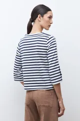 Remera de manga tres cuartos con diseño a rayas horizontales en azul marino y blanco. Presenta un detalle de volados laterales en las mangas y cuello redondo.