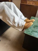 Pantalón de jogging gris melange de corte baggy, confeccionado en algodón. Presenta cintura elástica con cordón largo ajustable, bordado decorativo en la pierna izquierda y botones metálicos en la parte inferior de la botamanga para ajustar el ancho.