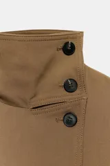 Chaqueta de cuello alto y manga larga en color marrón tostado. Presenta cierre frontal cruzado con botones oscuros, bolsillos de vivo en el delantero y un cinturón del mismo tejido con hebilla ajustable en la cintura.