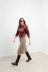 Falda midi de tiro alto confeccionada en tejido tweed con patrón de espiga en tono marrón. Presenta un diseño recto y cierre frontal con botones.
