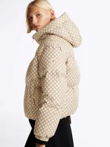 Campera acolchada con estampado distintivo en tonos beige y marrón. Cuenta con capucha fija, cuello alto, cierre de cremallera, bolsillos laterales y puños elásticos.