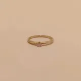 Anillo de oro 18k compuesto por una alianza fina con un brillante engastado y una estructura entrelazada de diseño moderno.