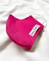 Tapabocas de tela color fucsia con elástico blanco y etiqueta con la marca Valente.