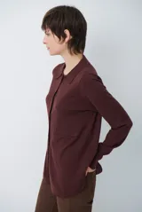 Cardigan de punto color beige, con cuello camisero, cierre frontal de botones y bolsillo aplicado en el pecho. Presenta mangas largas con puños acanalados y un corte recto y holgado.
